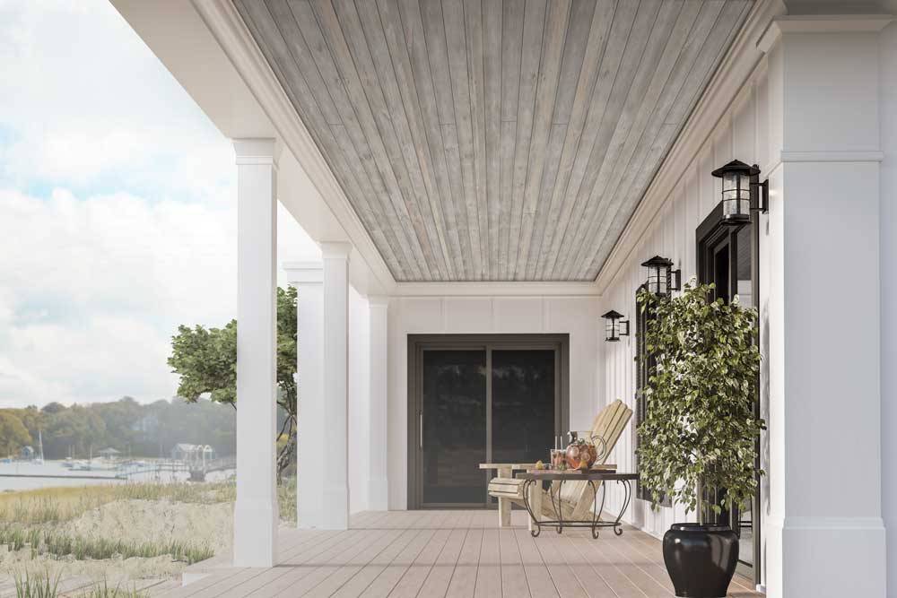 Covered porch with Easy Barnwood “Sterling Gray” plank ceiling, white columns and siding, black wall lanterns, and coastal water view.