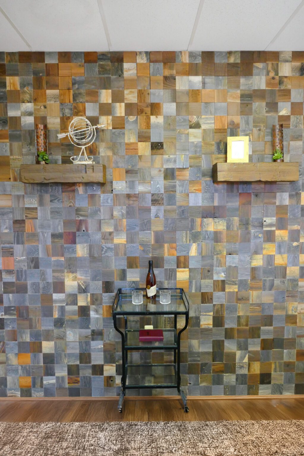 Reclaimed wood plank accent wall in mixed gray and brown tones with framed wall art above a small table and plant décor.