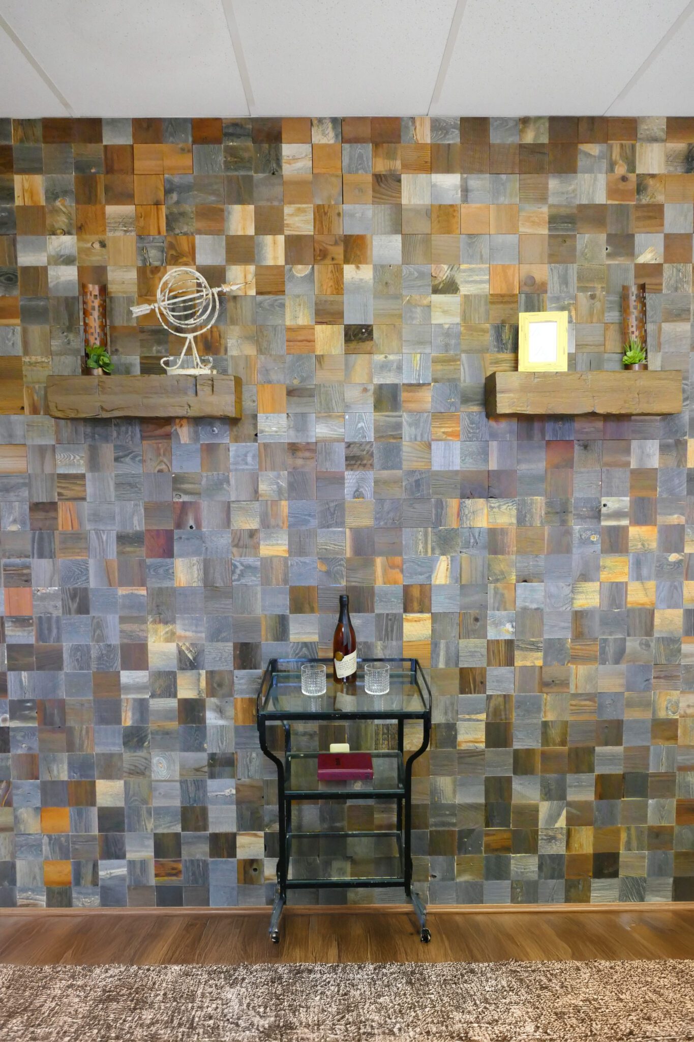 Reclaimed wood plank accent wall in mixed gray and brown tones with framed wall art above a small table and plant décor.