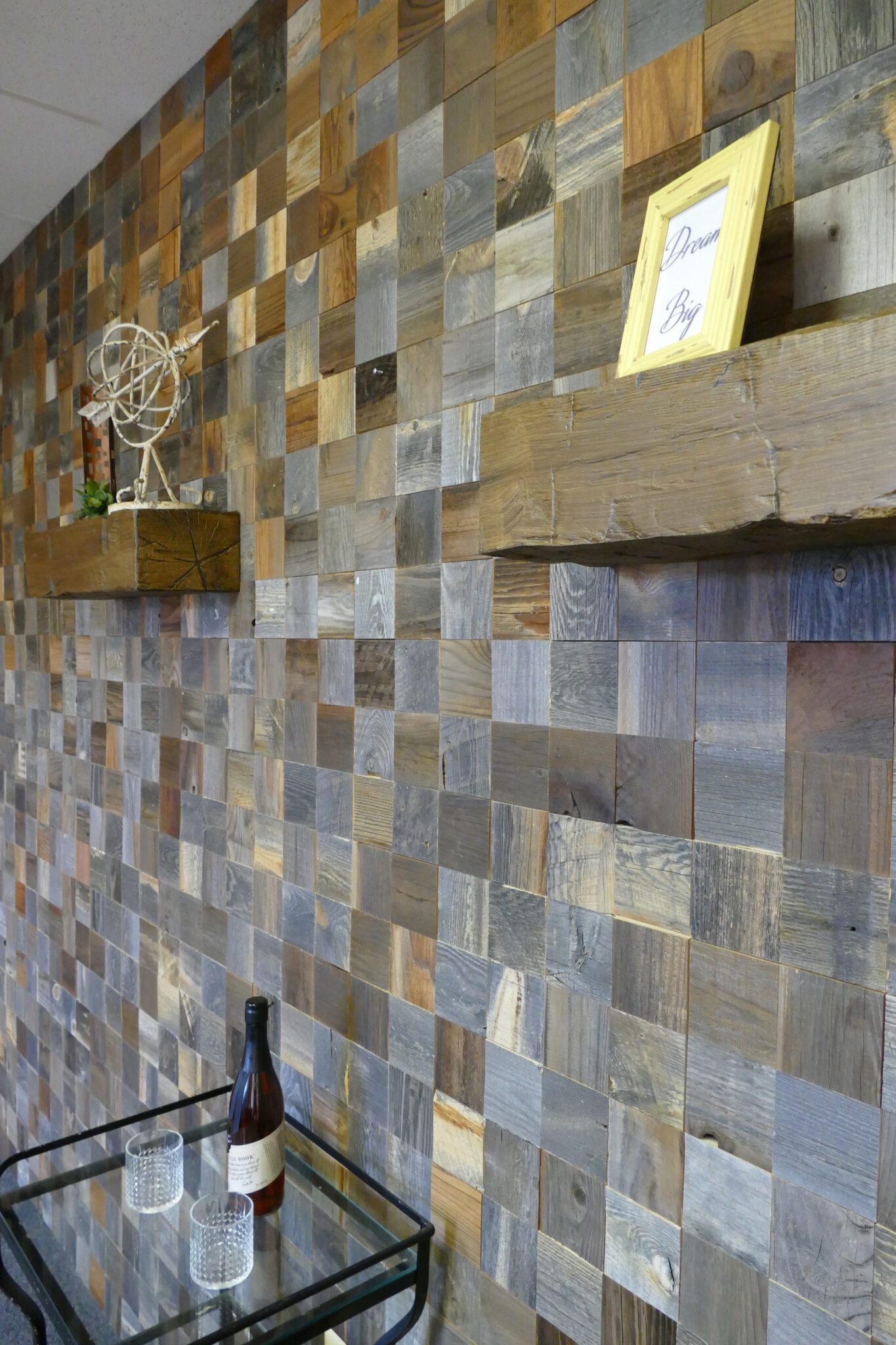 Wood square mosaic feature wall with floating shelves and a small bar cart.