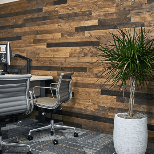 Reclaimed wood plank accent wall behind a desk in a modern office.
